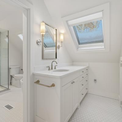 Bright, modern bathroom with skylights, shower, and white cabinets.