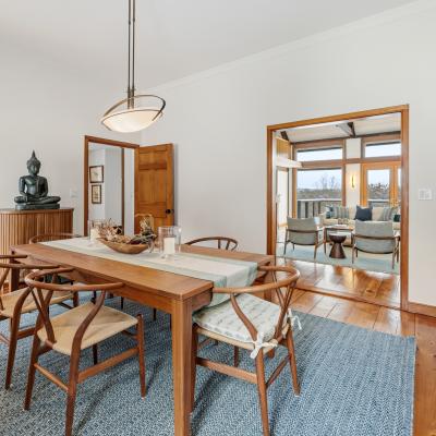 A stylish dining area featuring a wooden table, chairs, and a Buddha statue, with a view to another room.