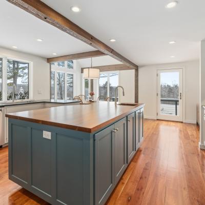 Modern kitchen with a wooden island, gray cabinets, and large windows for natural light.