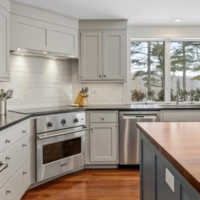Modern kitchen with gray cabinets, stainless appliances, and a view of trees outside.