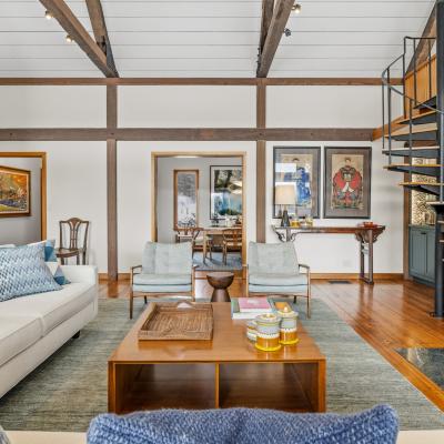 Cozy living room with modern decor, wooden beams, and a spiral staircase.