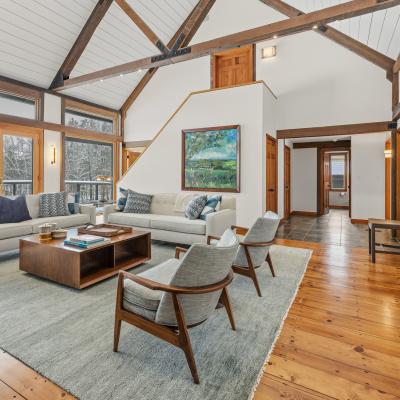 Modern living room with large windows, wood beams, and cozy furnishings.