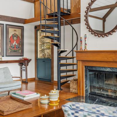 Modern living room with spiral staircase, artwork, and cozy furniture.
