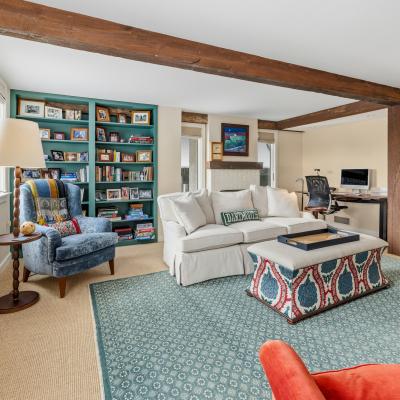 Cozy living room with a blue chair, white couch, colorful rug, and a bookshelf.