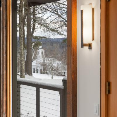 View of a snow-covered landscape with a house and trees seen through a window.