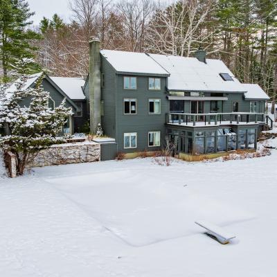 Modern house surrounded by snow-covered ground and trees in a winter landscape.
