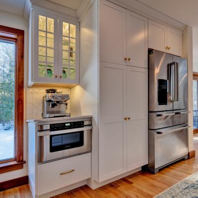 Modern kitchen corner with white cabinetry, stainless appliances, and window view.