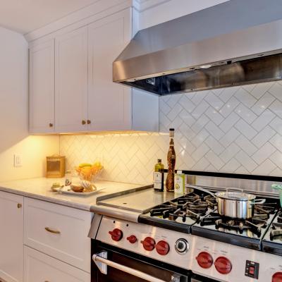 Modern kitchen with a gas stove, marble countertop, and decorative backsplash.