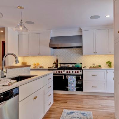 Bright, modern kitchen with white cabinets, a black stove, and marble countertops.
