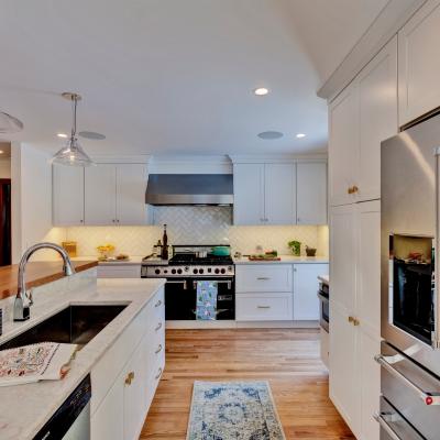 Modern kitchen with white cabinets, stainless appliances, and wood accents.