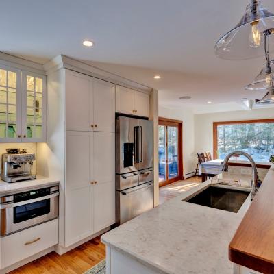 Modern kitchen with stainless appliances, wooden accents, and large windows.