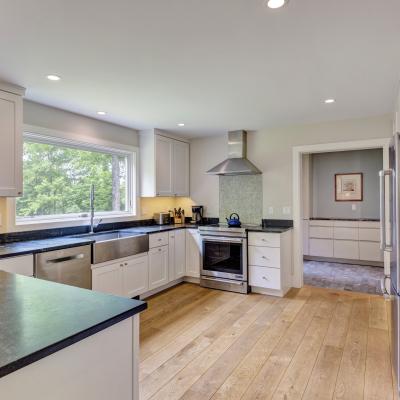 Bright modern kitchen with white cabinets, black countertops, and a large window.
