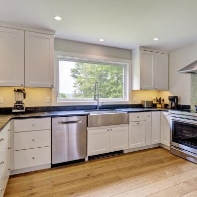 Modern kitchen with stainless steel appliances and large window overlooking greenery.