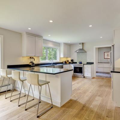 Modern kitchen with white cabinets, black countertops, and a large window for natural light.