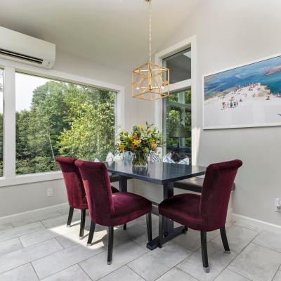 Modern dining area with a table, purple chairs, flowers, and a nature view outside.