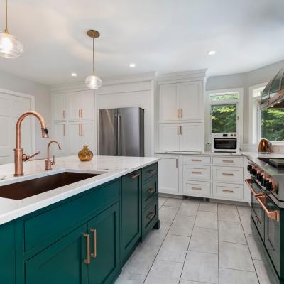 Modern kitchen featuring green cabinets, marble countertops, and copper accents.