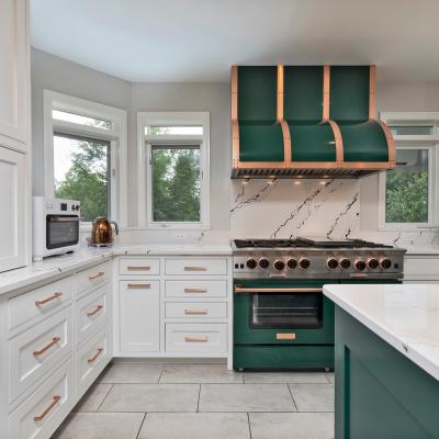Modern kitchen with green and copper accents, featuring a gas stove and marble countertops.