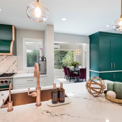 Modern kitchen with green accents, marble countertops, and a stylish dining area.