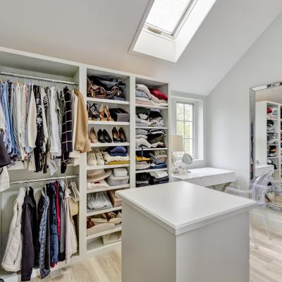 Stylish closet with organized clothing, shoes, and a vanity area.