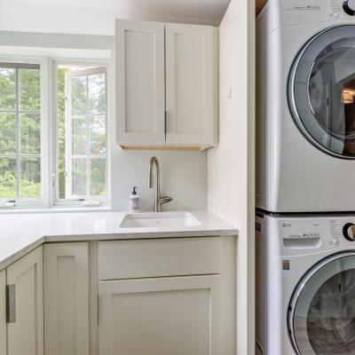 Laundry room featuring stacked washer and dryer, sink, and large windows.
