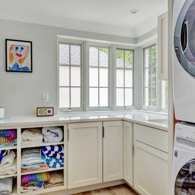 Bright laundry room with shelves of neatly folded towels and a washer-dryer unit.