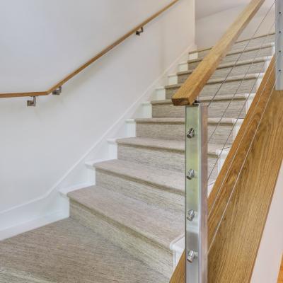 Modern staircase with wooden railings and carpeted steps, leading to a light-filled entry.