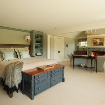 Spacious bedroom with a large bed, a wooden dresser, and cozy seating area.