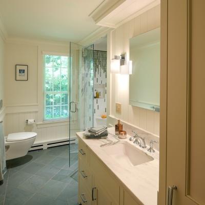 Bright bathroom with a glass shower, white vanity, and natural light from a window.