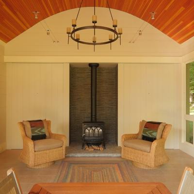 Cozy interior with two wicker chairs, a wood stove, and rustic decor elements.
