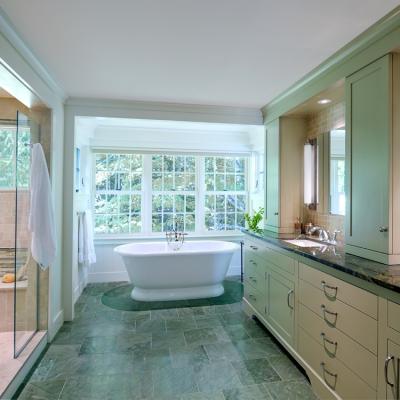 Bright, modern bathroom with a freestanding tub, sleek cabinetry, and large windows.