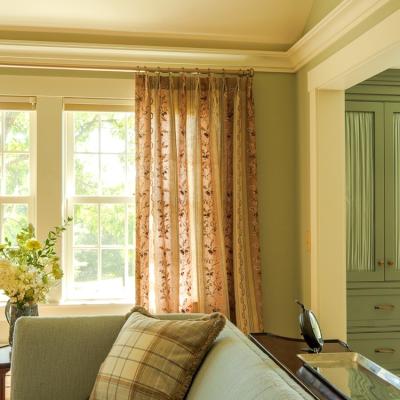 Bright, airy living room with floral curtains and a vase of flowers on a table.