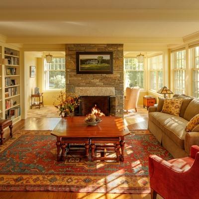 Cozy living room with a stone fireplace, bookshelves, and warm lighting.
