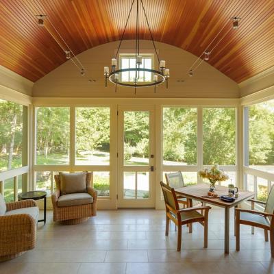 Bright sunroom with tall windows, a wooden ceiling, and garden views, featuring cozy seating.