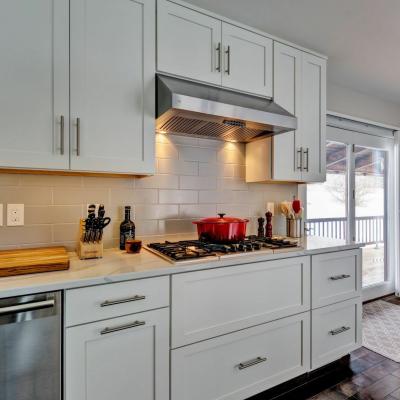 Modern kitchen with white cabinets, gas stove, red pot, and wooden cutting board.