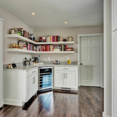 Modern kitchen corner with shelves, a wine fridge, and large windows.