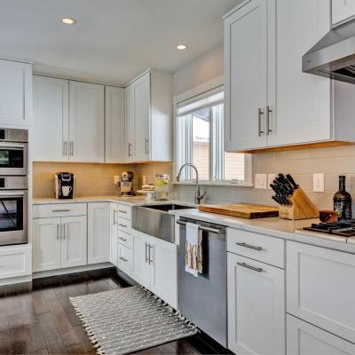 Modern kitchen with white cabinets, stainless steel appliances, and a wooden cutting board.