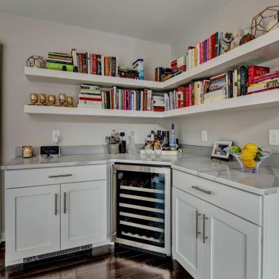 Modern kitchen nook with bookshelves, wine fridge, and a bowl of lemons.