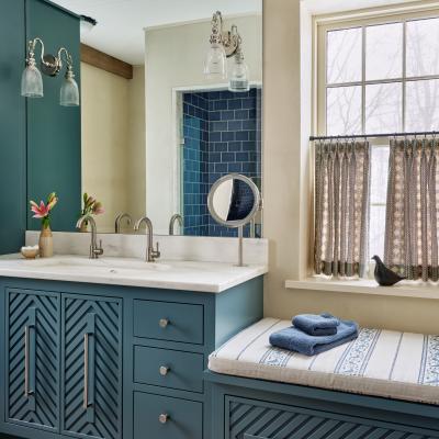 Stylish bathroom with teal cabinetry, marble sink, and decorative curtains.