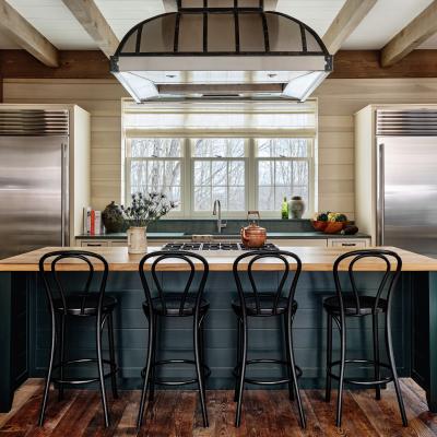 Modern kitchen with wooden island, black chairs, and stainless steel appliances. Bright and airy.