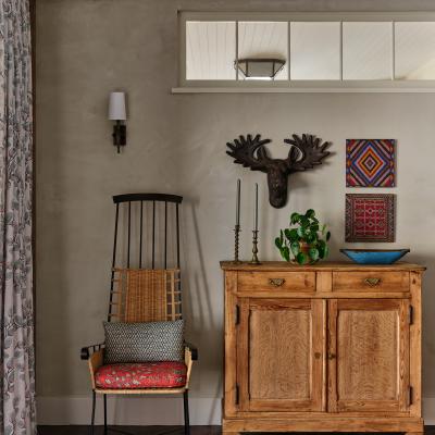 Cozy interior with a vintage chair, wooden cabinet, and decorative art pieces on the wall.