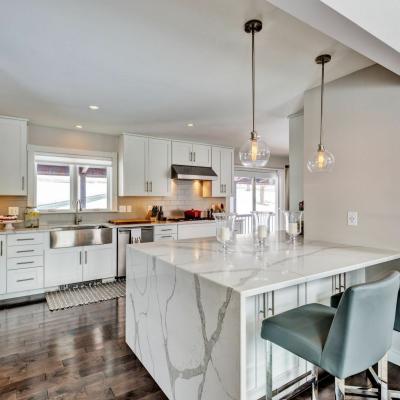 Modern kitchen with white cabinetry, marble island, and pendant lighting.