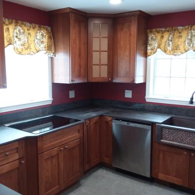 Modern kitchen with wood cabinets, dark countertops, and yellow floral curtains.
