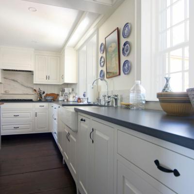 Bright kitchen with white cabinets, dark countertop, and decorative plates.