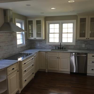 Bright, modern kitchen with white cabinets, stainless appliances, and a stone countertop.
