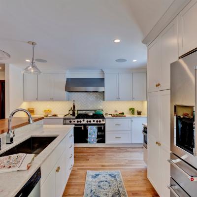 Modern kitchen with white cabinets, stainless appliances, and a wooden countertop.