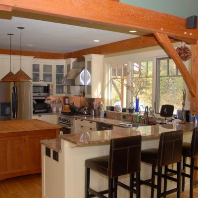Modern kitchen with wooden beams, granite countertops, and an island with bar stools.