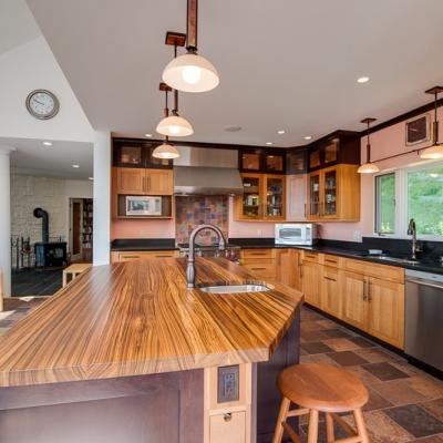 Modern kitchen features a large wooden island, sleek cabinetry, and natural light.