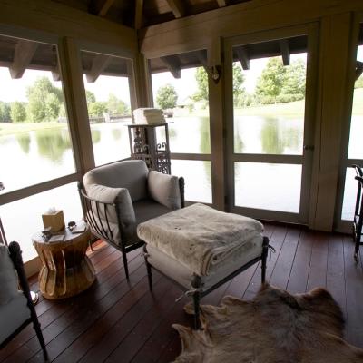 Cozy room with seating, wooden decor, and a lake view through large windows.