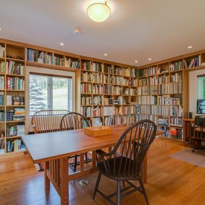 Bright, cozy library with wooden bookshelves, a table, and two chairs.