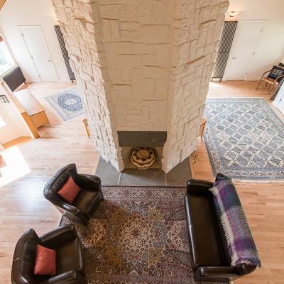 Spacious living room with a stone fireplace, two chairs, and decorative rugs.